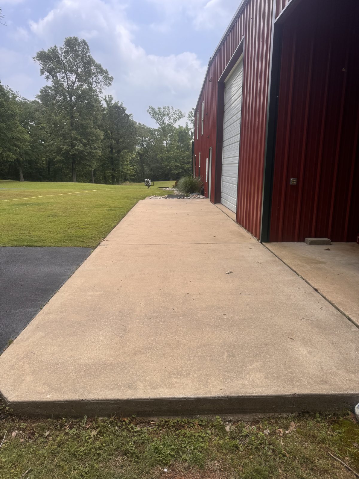 Freshly cleaned concrete apron along a red metal building in Haughton, LA