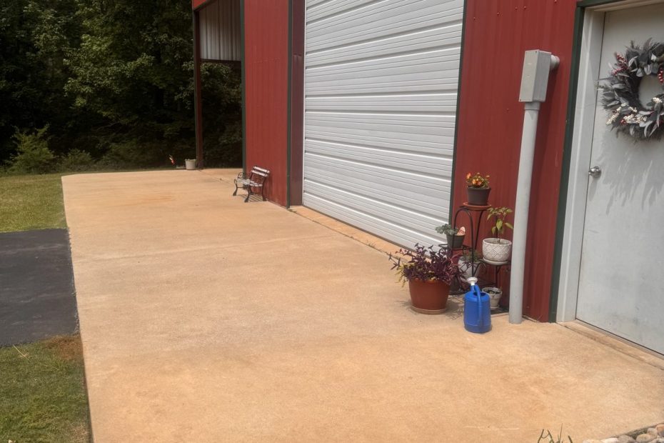 Washed concrete pad in front of a red metal building garage door in Haughton, LA