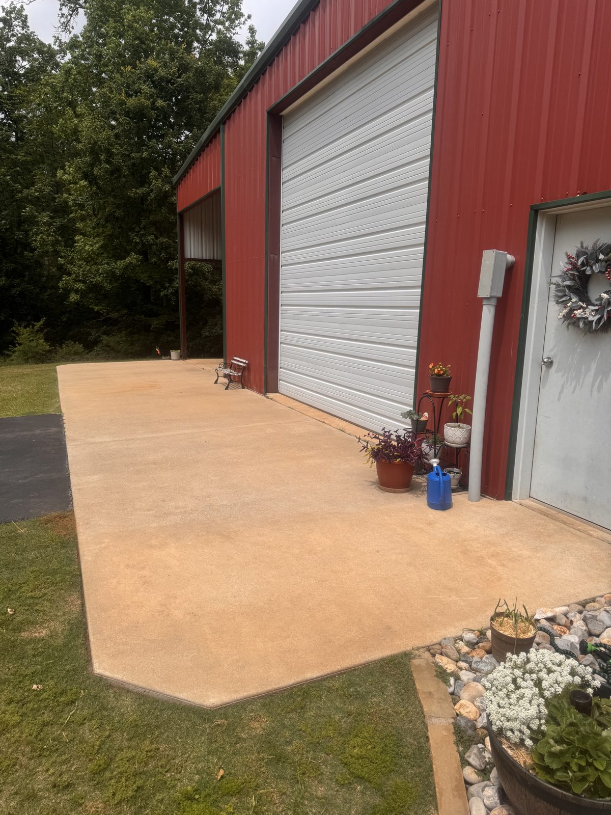 Washed concrete pad in front of a red metal building garage door in Haughton, LA